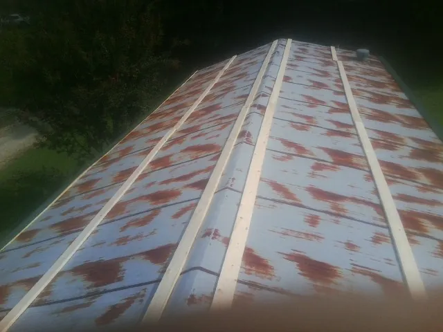 Rusted metal roof panels with new wood purlins before replacement — Storm Damage Roof Repair in Granby by Roofing Brothers