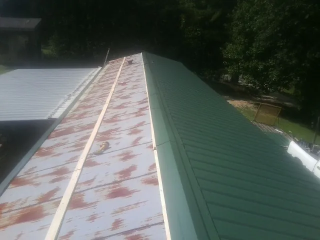 Old rusted panels beside newly installed green metal roofing — Wind Damage Roof Repair by Roofing Brothers in Granby