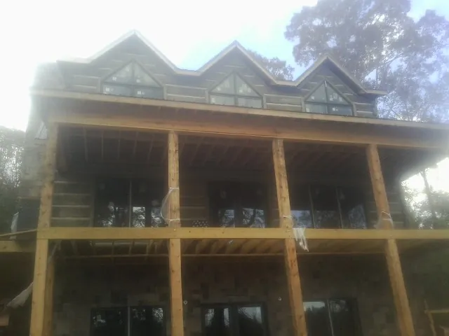 Dormers and porch framing on a large log home under construction — Roof Coating work by our crew in Granby